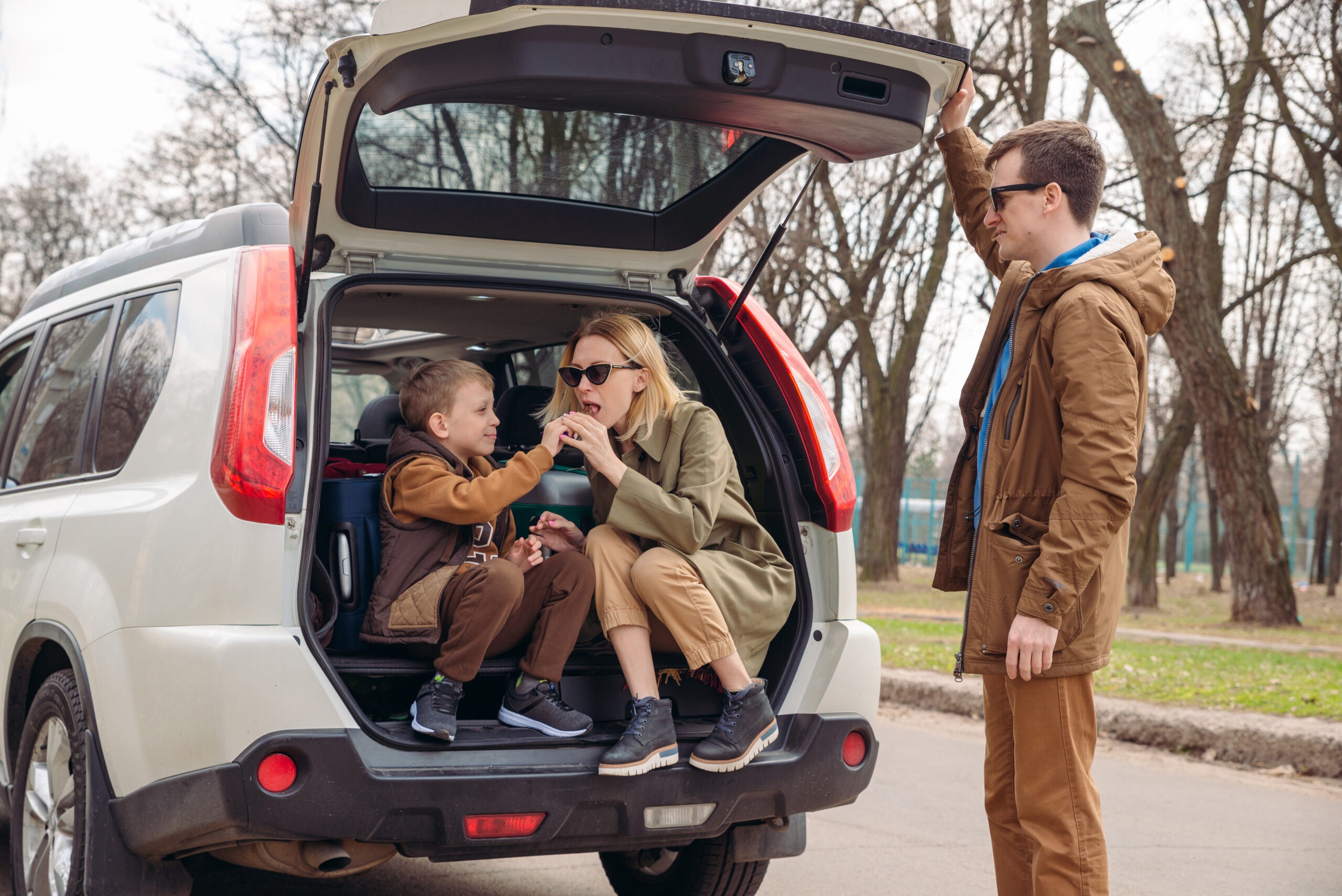 young family packing for car travel. putting bags into trunk. road trip